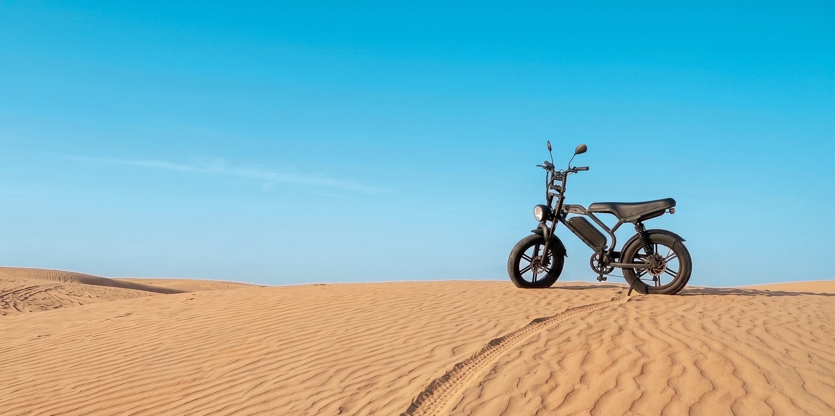 E-bike INOW estacionada no alto de uma duna, sob céu azul